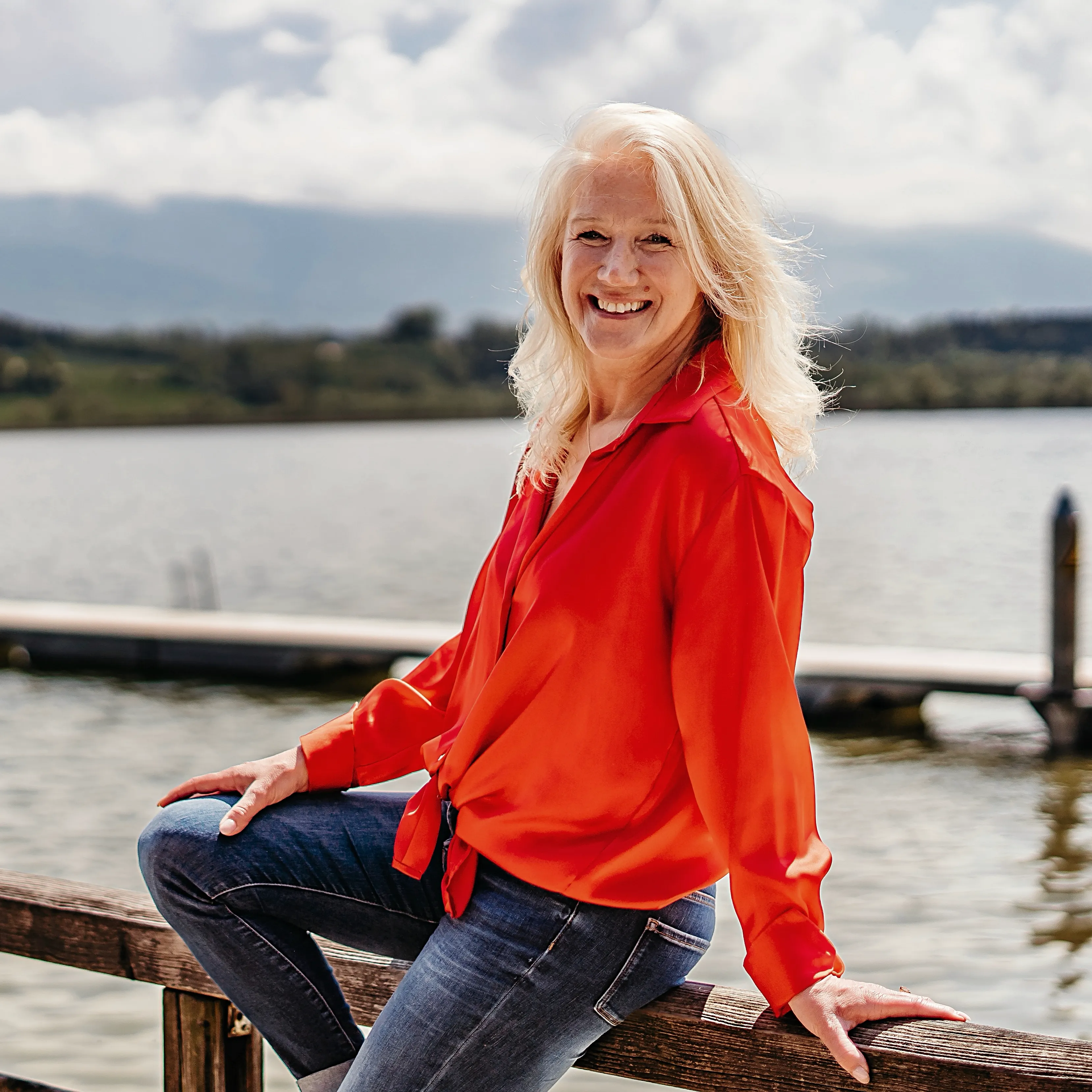 Starkes Coaching für starke Frauen | Sabine Kohl Coaching Sabine Kohl mit roter Bluse auf Geländer am See