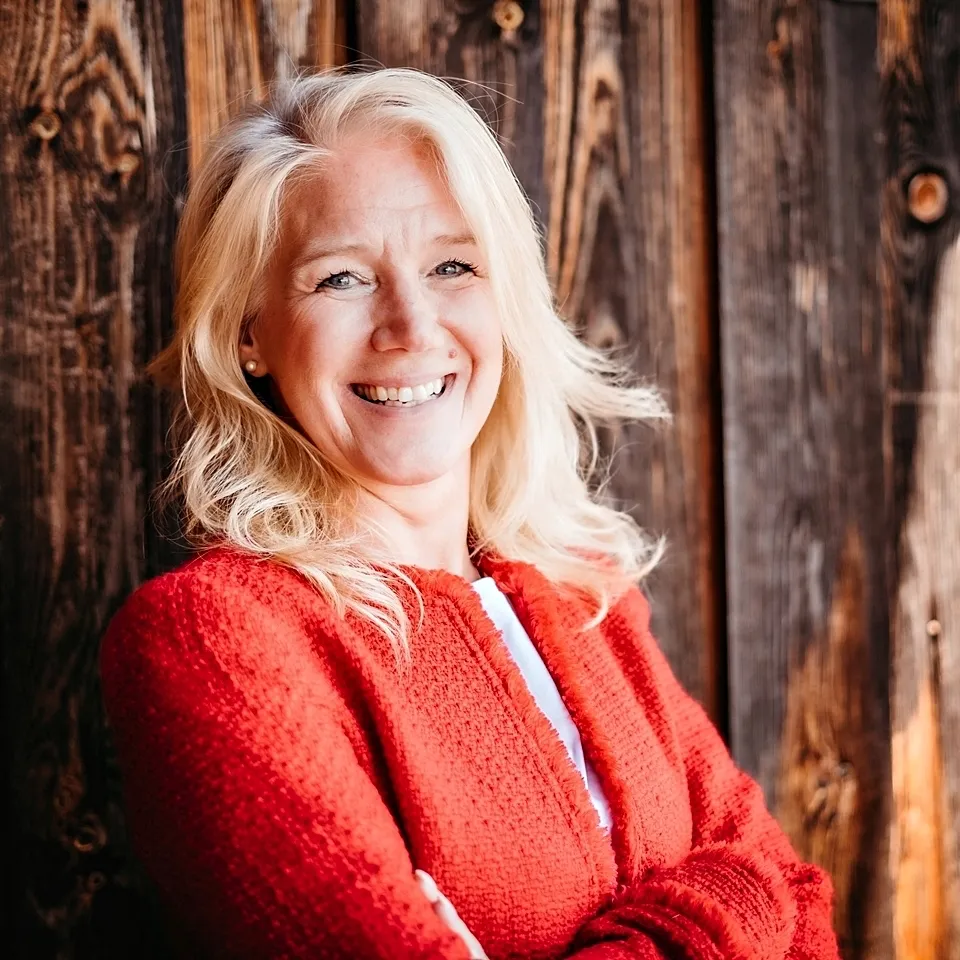 Starkes Coaching für starke Frauen | Sabine Kohl Coaching Sabine kohl mit roter Weste vor Holzschoine